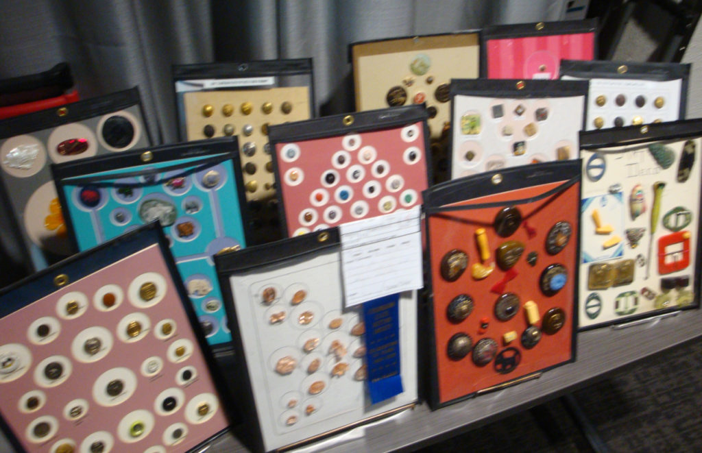 Table covered with frames containing unique buttons of different types, including one frame with a blue ribbon award.